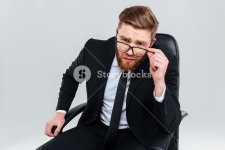 graphicstock-serious-bearded-business-man-in-glasses-looking-at-camera-and-sitting-on-armchair...jpg